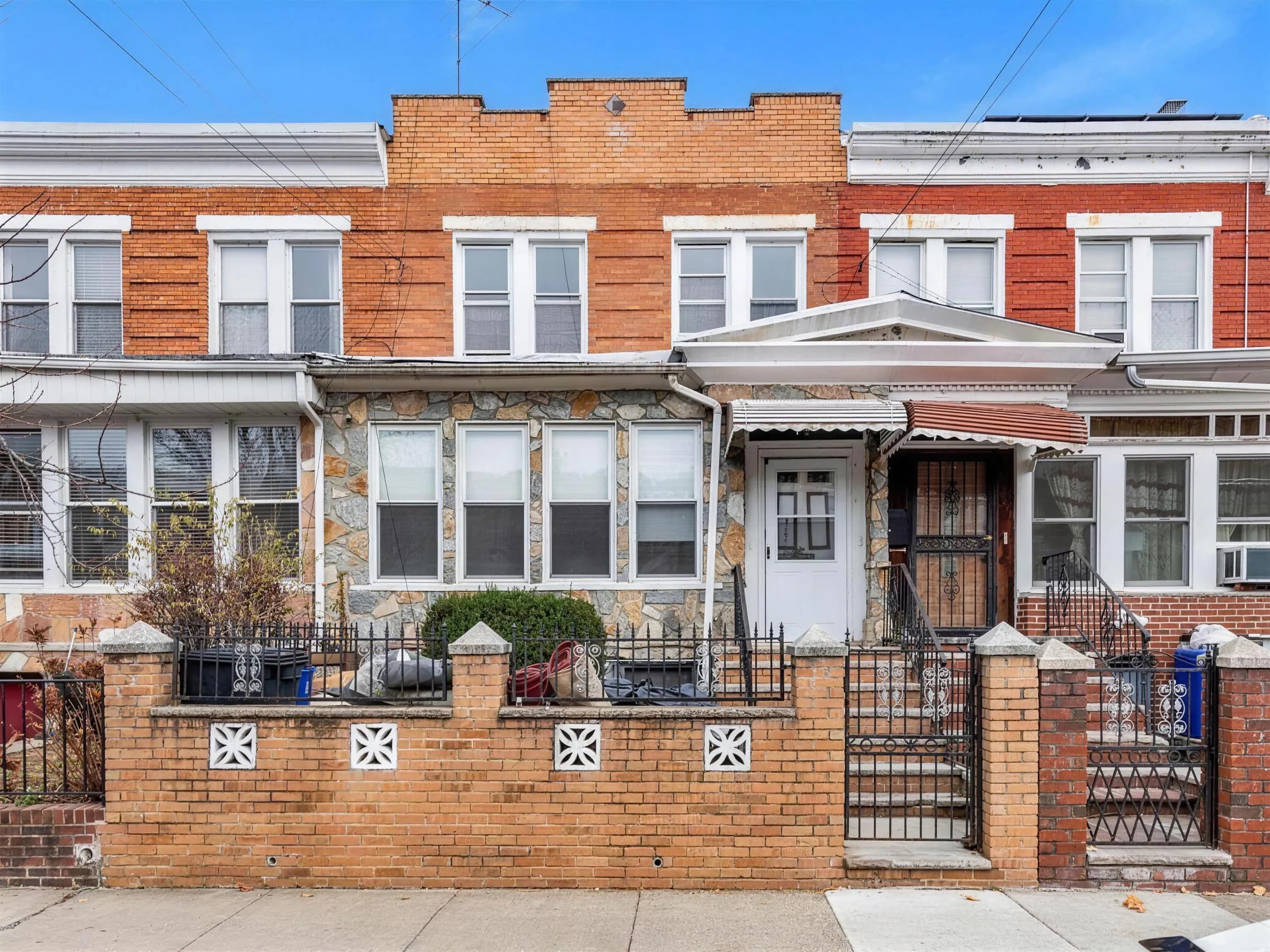 A row of attached brick and stone houses with front gates along a city block